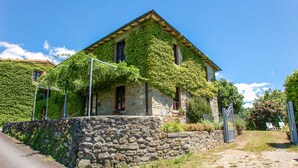A stone house with a sloped roof, ivy-covered walls, and a stone wall in front. - House with private pool at 2,8 km from Castiglione di Garfagnana. Panoramic view (villa collemandina)