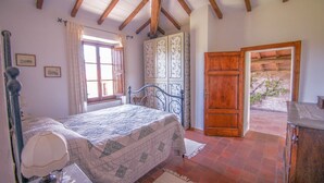 A bedroom with a bed, a nightstand, a window with curtains, a wooden wardrobe, and a door leading to an outdoor area. - House with private pool at 2,8 km from Castiglione di Garfagnana. Panoramic view (villa collemandina)