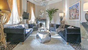Un salón lujoso con chimenea, muebles elegantes y detalles decorativos.