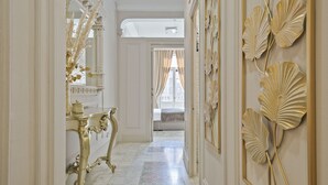 Un pasillo lujoso con detalles dorados ornamentales, un espejo y una cama al fondo.