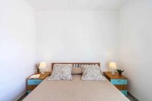A bedroom with a bed, two bedside tables, and a nightstand.
