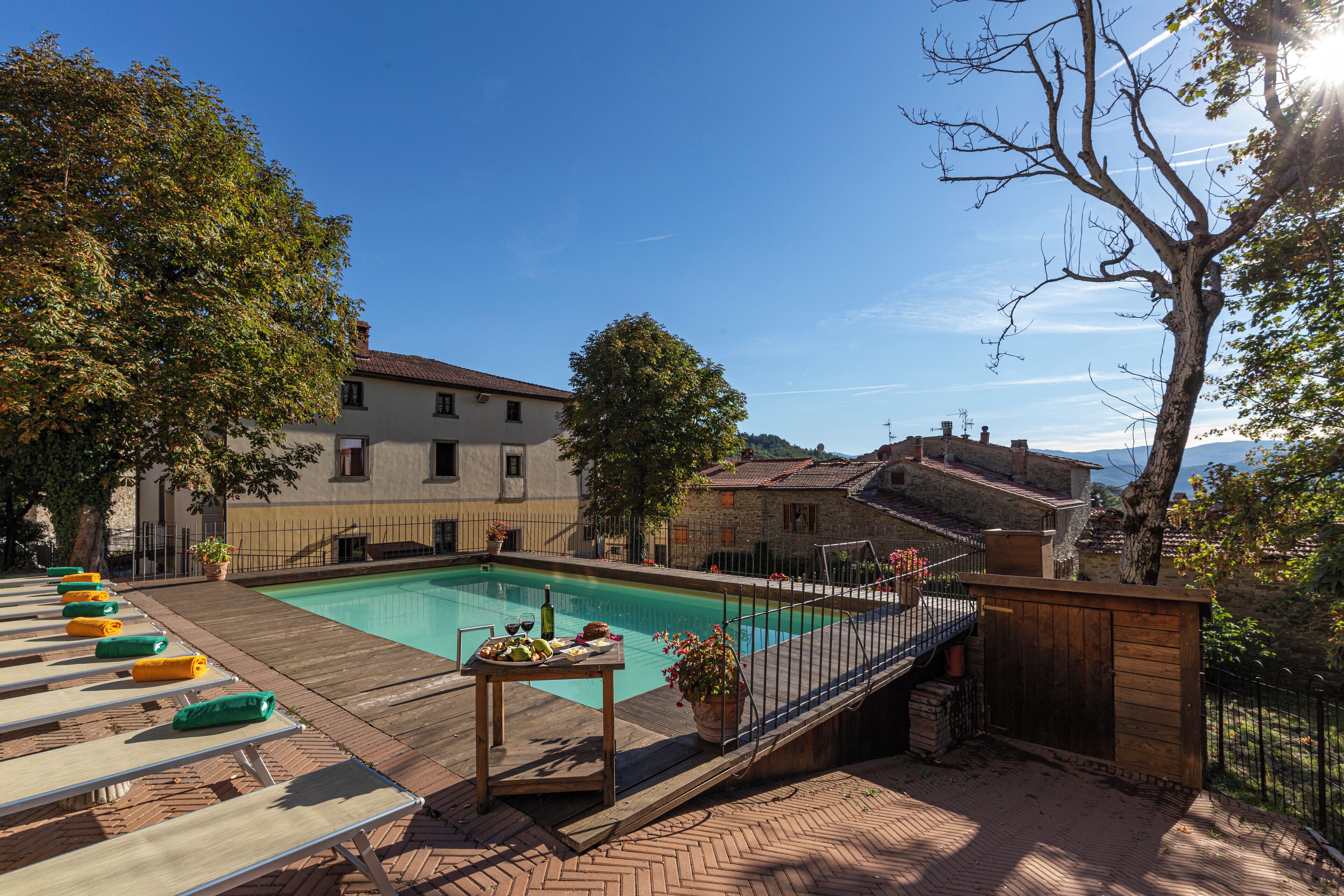 A pool area with lounge chairs, a table with food, and a wooden deck.