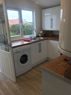 Een magnetron, een oven, een vaatwasser, kookgerei, borden en bestek