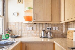 Une cuisine dotée de meubles en bois, d’un crédence carrelée et d’appareils électroménagers, notamment une bouilloire et un grille-pain.