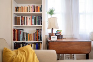 A room with a bookshelf, a desk with a lamp, and a window with curtains.