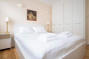 A hotel room with a bed, two bedside lamps, a painting, and a wardrobe. - Brilliantly Located 2BD Flat by Buckingham Palace (London)