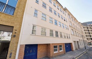 Un immeuble à plusieurs étages, doté d’une façade beige, de nombreuses fenêtres et d’une porte bleue portant l’inscription « 10 ».