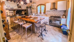 Una cocina amplia con una isla grande, taburetes de madera, estufa a gas y microondas.