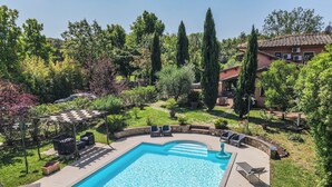 Una piscina rectangular con solárium empedrado, rodeada de sillones de descanso y una pérgola.