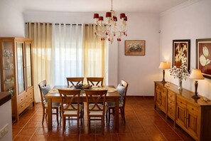 A dining area with a wooden table and chairs, a chandelier, and a cabinet with glass doors.