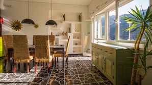 Un comedor con sillas de mimbre, una mesa y un armario verde con vista a una ventana.