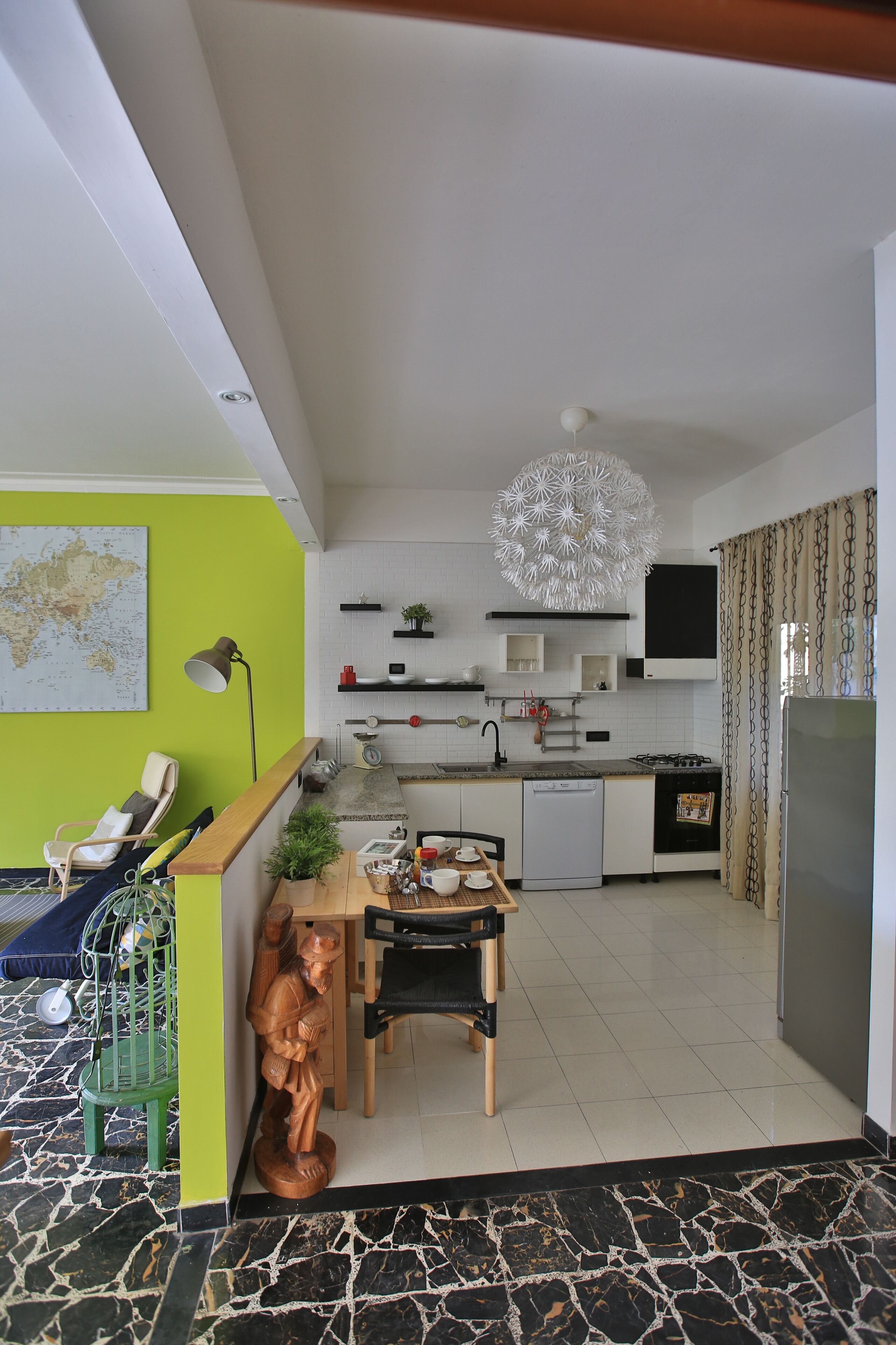 Una cocina moderna con armarios blancos, estufa y lavavajillas. Hay un comedor con mesa y sillas.