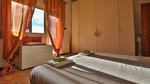 Un dormitorio con cama, armario y ventana con cortinas.