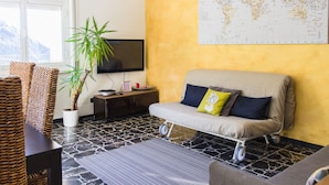 Una sala de estar con un sofá, un televisor, una planta en maceta y un mapa mundial en la pared.