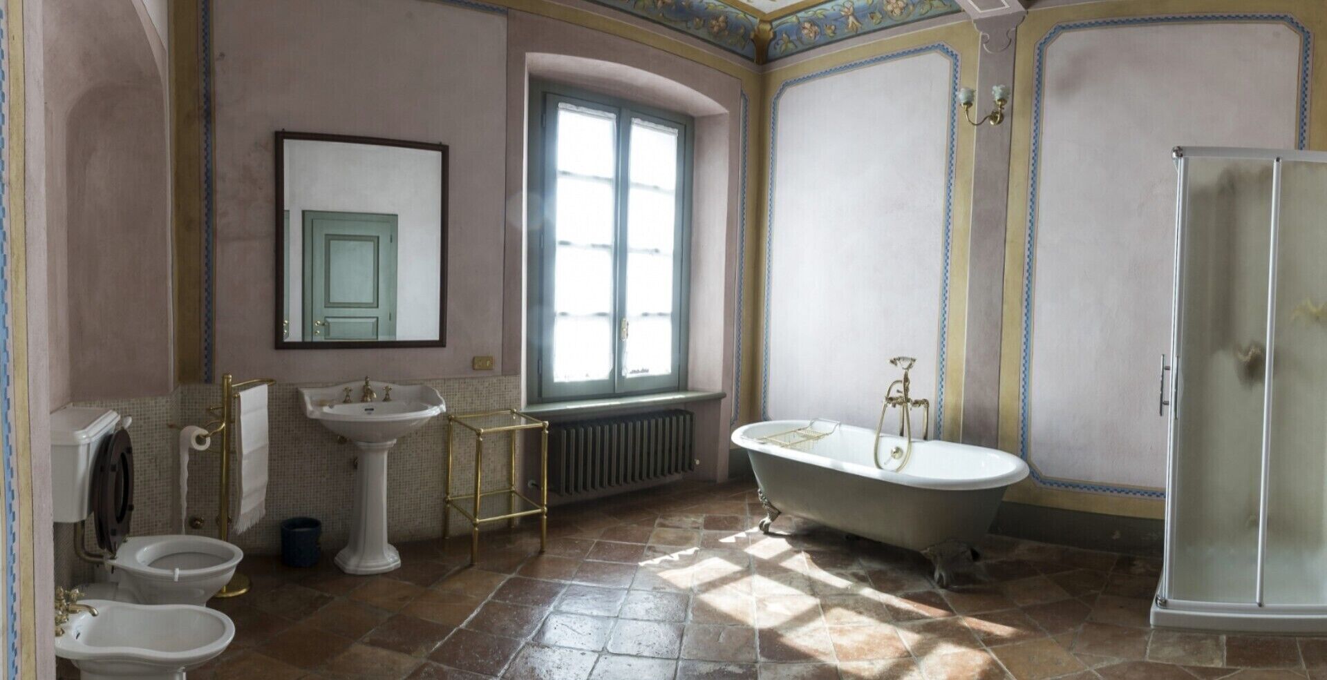 A bathroom with a bathtub, two sinks, a toilet, and a window.