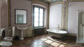 A bathroom with a bathtub, two sinks, a toilet, and a window.