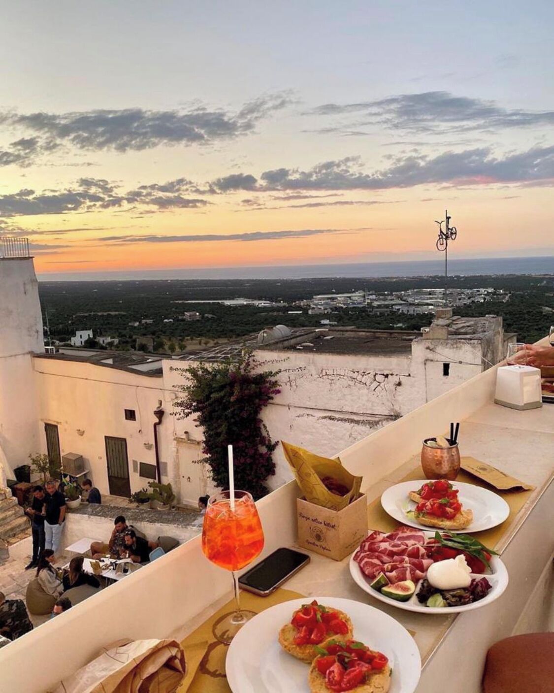 Una terrazza panoramica sul tetto con vista al tramonto, posti a sedere all'aperto e servizio di cibo e bevande.
