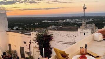 Una terrazza panoramica sul tetto con vista al tramonto, posti a sedere all'aperto e servizio di cibo e bevande.