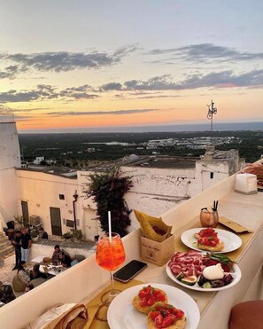 Une terrasse sur le toit offrant une vue sur le coucher du soleil, des places assises en plein air et un service de restauration et de boissons.