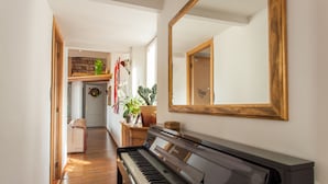 Um piano em um corredor com um espelho e uma porta que dá para um quarto.