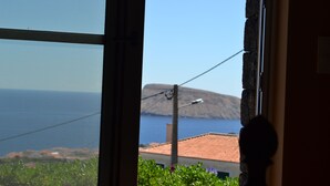 Blick durch ein Fenster auf eine Stromleitung, einen Berg und ein Gewässer.