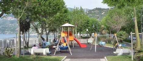 Un parc avec une aire de jeux, des bancs et une vue sur la mer.