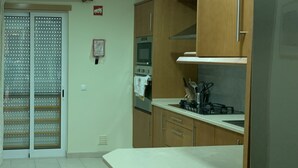 A kitchen with wooden cabinets, a white countertop, a stove, and a refrigerator.