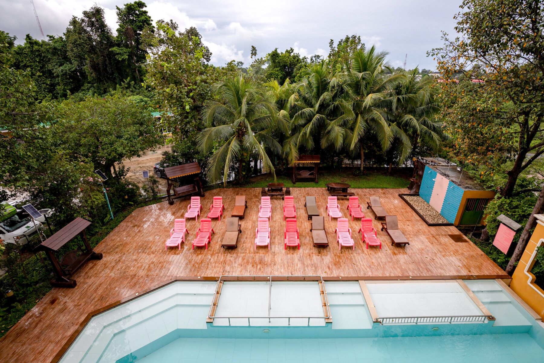 A pool area with multiple lounge chairs and a wooden deck.