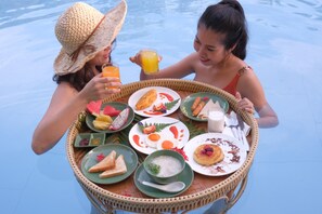 A dining table with various dishes and drinks, surrounded by a pool. - ROYAL PINEAPPLE HOTEL | A Welcome to Wealth and Good Fortune (Krabi)