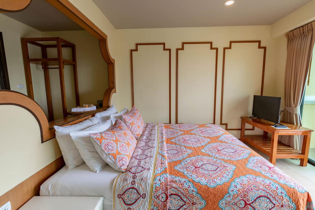 Ein Hotelzimmer mit einem großen Bett, einem Fernseher und einem Nachttisch aus Holz.