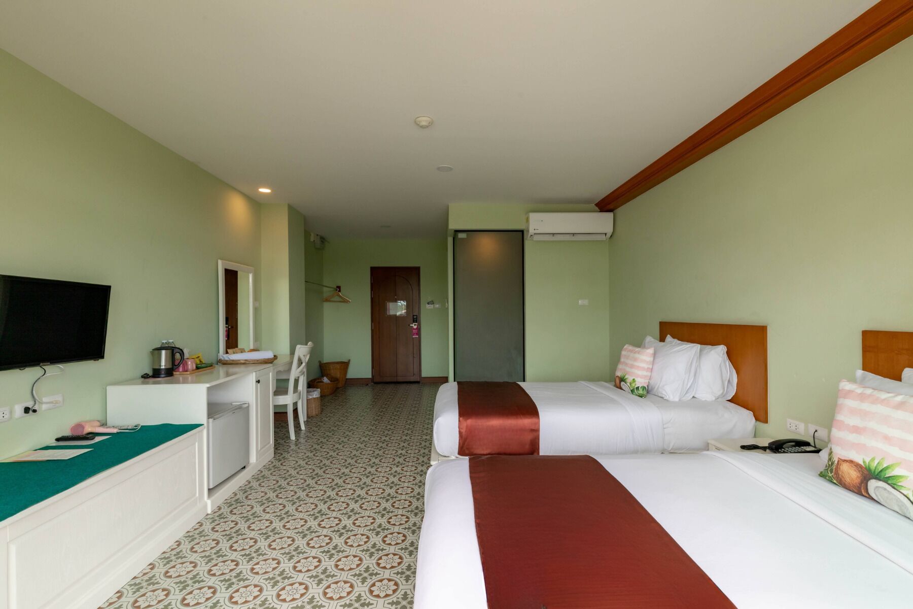 A hotel room with a bed, a desk, a television, and an air conditioning unit.