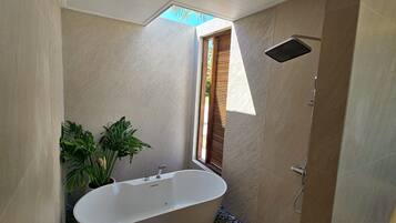 A modern bathroom with a freestanding bathtub, a showerhead, and a window with blinds.