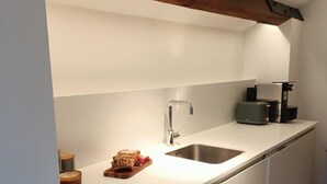 Eine moderne Küche mit weißer Arbeitsplatte, Spüle aus Edelstahl und Holzbalken darüber.