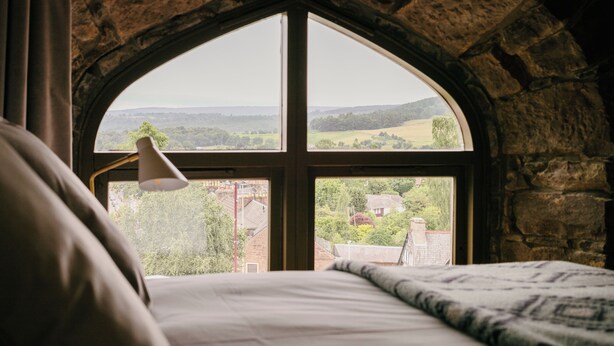 Ein Schlafzimmer mit einem spitzbogigen Fenster mit Blick auf eine ländliche Landschaft.