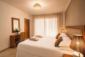 Ein Hotelzimmer mit einem großen Bett, einem Schreibtisch mit Stuhl, einem Spiegel und einer Lampe.