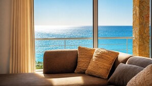 A room with a large window overlooking a body of water, a sofa with textured cushions, and a stone pillar.
