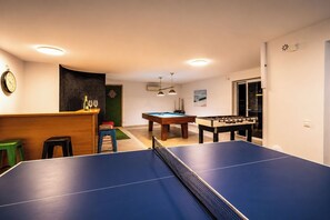 Ein Raum mit Tischtennisplatte, Billardtisch und Kicker.