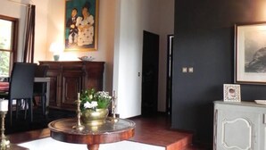 A room with a wooden ceiling, a dining area with a table and chairs, a black leather rug, and a cabinet with a framed picture. - Villa Leglise Chafe plage d' Amorosa - Viana - pets welcome. (Chafé)