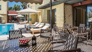 Ein Poolbereich mit Liegestühlen, Sonnenschirmen und einem Tisch mit Wassermelone und Laterne.