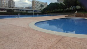A swimming pool with a hexagonal tile pattern, surrounded by a low stone wall and a paved area. - FANTASTIC LOFT APARTMENT ON THE BEACH WITH ALL SERVICES (WIFI, A / C) (Alicante)