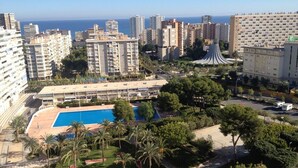 A high-rise hotel with a swimming pool, surrounded by palm trees and other greenery. - FANTASTIC LOFT APARTMENT ON THE BEACH WITH ALL SERVICES (WIFI, A / C) (Alicante)