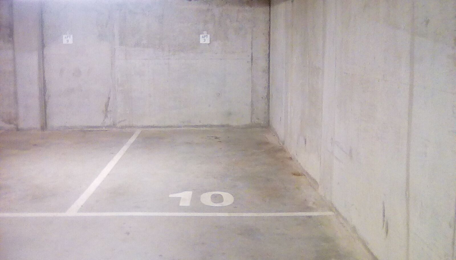 A parking space marked with the number 10, surrounded by concrete walls.