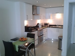 Enjoy cooking in this well-equipped kitchen with a stainless steel range, compact microwave, and dining table for meals.