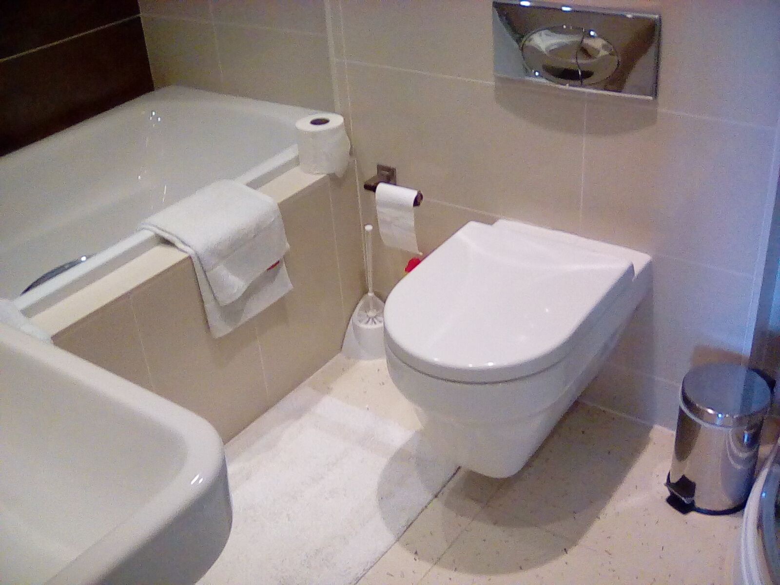 Un baño con bañera, inodoro y un cubo de basura.