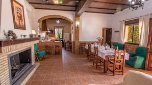 A dining area with a brick fireplace, wooden chairs, and a table set for a meal.