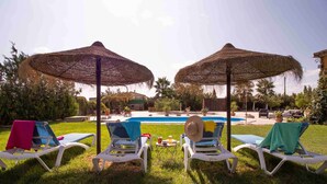 A poolside area with lounge chairs and thatched umbrellas.