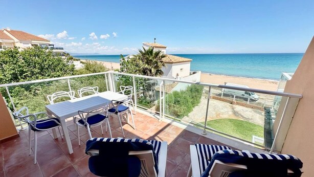 Balcón con mesa y sillas, con vista a la playa y al océano.