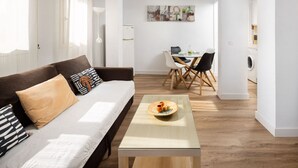 Ein modernes Wohnzimmer mit einer Couch, einem Couchtisch und einer Essecke mit Stühlen.