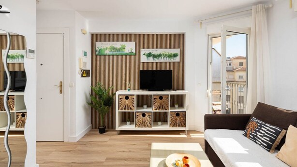 Ein modernes Wohnzimmer mit Fernseher, Holzregalen und einer Couch.