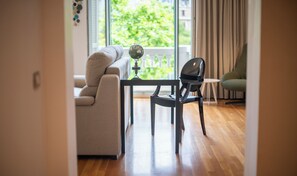 Un salon moderne avec un canapé, une table à manger, une chaise et une vue sur la verdure à l’extérieur.